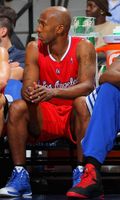 Chauncey Billups sits and looks on from the bench in a red Clipper jersey.JPG